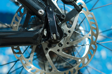 Fototapeta na wymiar Disk brake of mountain bike close up on a blue wall background.