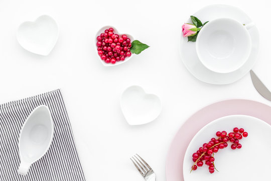 set-up table with plates, wineberry and flower on white background top view