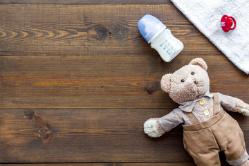 Handmade toys for newborn baby. Teddy bear. Feeding bottle with milk and dummy. Wooden background top view mockup