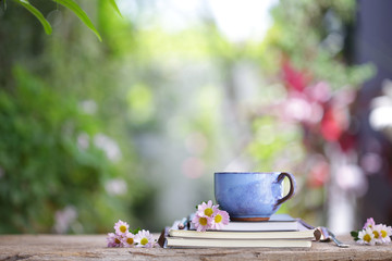 Old blue cup and notebook with flower on wooden table