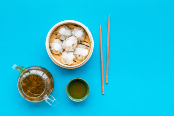 Dinner in Chinese restaurant with dim sum, sticks and herbal tea on blue background top view