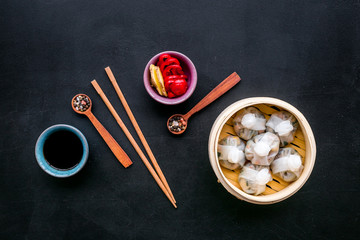 Dinner in Chinese restaurant with dim sum, sticks and tea on black background top view