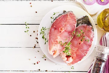 Photo sur Plexiglas Poisson Raw steak of carp fish with lemon and thyme  on white wooden background. Preparing fish for roasting in parchment paper. Diet menu. Top view. Flat lay