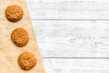 Cook homemade cookies. Pattern with fresh cookies on baking paper on white wooden background top view copy space