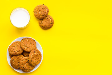 Drink milk with cookies concept. Cup of milk and fresh homemade cookies on yellow background top view copy space