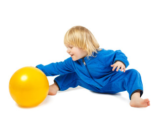 Cute baby boy sits on a floor and plays with yellow ball