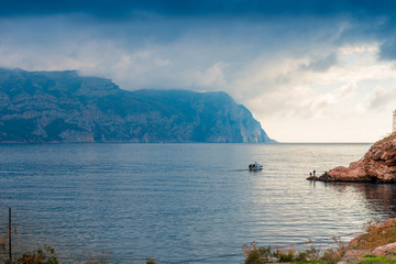 Fishing boat leaves in the sea, the sea and mountains landscape and dramatic sky