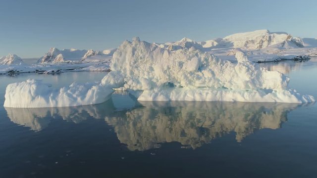 Iceberg Melt in Clear Ocean Water Drone Above View. Huge Ice Float in Reflection Water, Global Climate Warming Concept Pan Left Flight. Winter Polar Glacier Majestic Panorama Footage Shot in 4K (UHD)