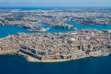 Fototapeta premium Malta aerial view. Valetta, capital city of Malta, Grand Harbour, Senglea and Il-Birgu (Vittoriosa) towns, Fort Ricasoli and Fort Saint Elmo from above. Marsaxlokk city and Freeport in background
