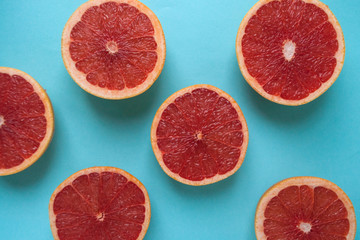 Creative background made of cut coral color grapefruits on blue background. Flat lay style.
