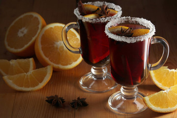 Two cups with ready mulled wine with anise, cinnamon and nuts around	