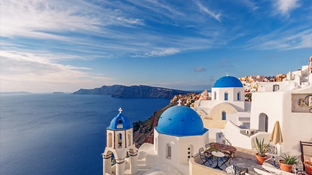 Churches in Oia, Santorini island in Greece, on a sunny day with dramatic sky. Scenic travel background. 4K timelapse.