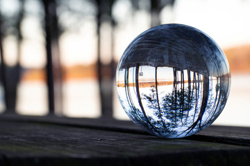 Inverted lake seen through glass ball on table in late afternoon