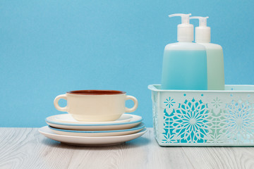 Bottles of dishwashing liquid and plates on blue background.