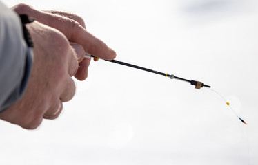 Fototapeta premium Man catches fish on ice in winter