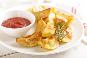 Potato baked and tomato ketchup on white plate, wooden background