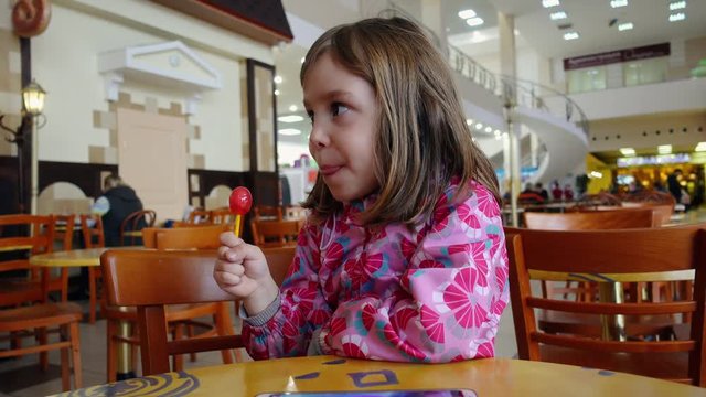 Eating and childhood concepts. A little girl, a child of 4-5 years old, eats chupa chups.