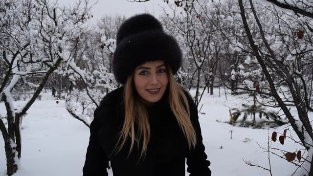 Portrait of a beautiful girl in a hat in the winter forest on the background of snow branches.