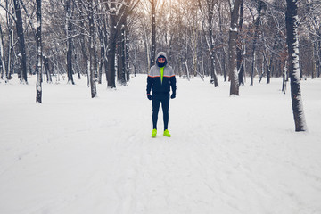 Man jogging in snowy park and cold weather.