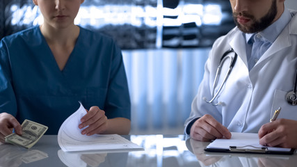 Female doctor giving bribe to head physician, dishonest people, corruption
