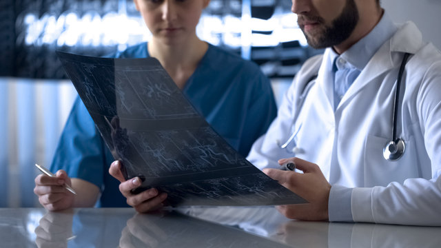 Neurosurgeon and anesthetist discussing cerebral vessels x-ray before operation