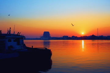 Fototapeta na wymiar Silhouette boat docking in riverside with long shore and beautiful sunrise sky in sunset time