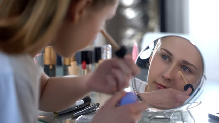 Lady skillfully applying face foundation, morning makeup, facial skin care