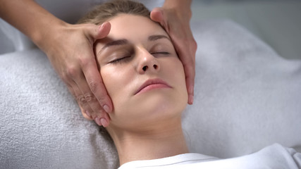 Obraz na płótnie Canvas Cosmetologist moisturizing clients skin, massaging face skin, anti-age effect