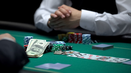 Rich businessman playing poker going all-in with house keys, money and chips