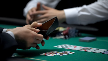 Croupier taking all chips and money, upset poker player showing empty wallet
