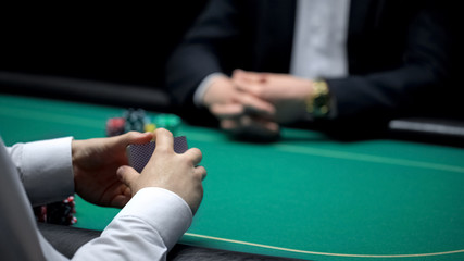 Male croupier shuffling cards at casino, ready to start poker game with client