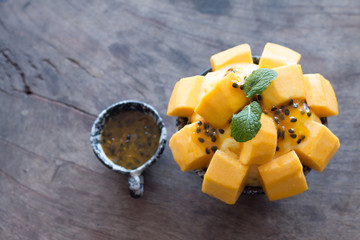 Refreshing mango ice cream and passion fruit in ceramic bowl on wooden desk for favorite summer...