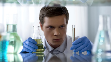 Unsure scientist looking at chemical substance in test tube waiting for reaction