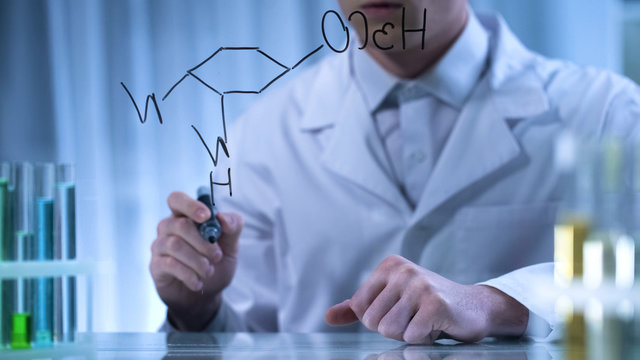 Pharmacist writing structural chemical formula on transparent board, research