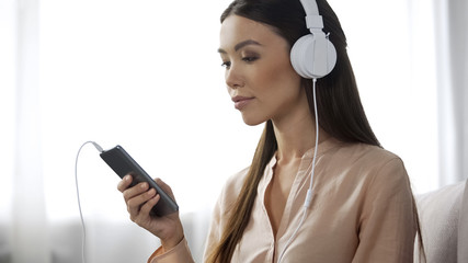 Asian woman listening music in headphones, loving radio station, enjoyment