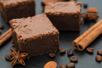 Chocolate brownie. On dark background decorated with cinnamon and coffee beans