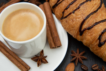 Breakfast set. Coffee with croissant decorated with cinnamon quills and star anise
