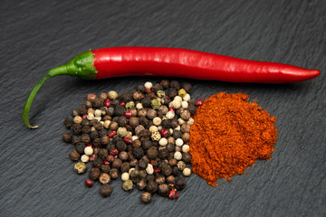 Red raw chili pepper, chili ground powder and mised peppercorns. On dark background © savanno
