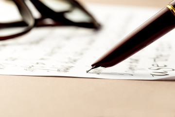 vintage fountain pen writing a letter, glasses behind