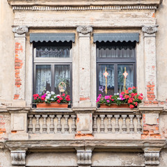 Obraz premium windows with geranium flower pots, old house facade detail