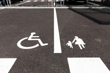 Handicap and Mother with child parking signs on asphalt.