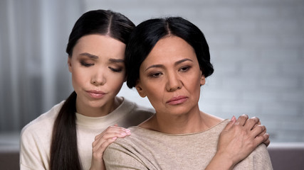 Asian daughter supporting worried mother, problems with health, aging process