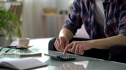 Man calculating income and expenses, deferring money for travelling, weekends