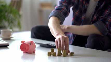 Man taking coins from table near empty piggy bank, last savings, poverty concept