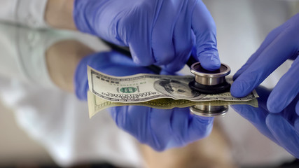 Expert examining dollar with stethoscope, devaluation concept, GBP decrease