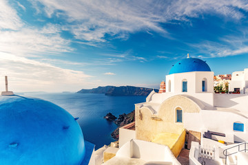 Churches in Oia, Santorini island in Greece, on a sunny day with dramatic sky. Scenic travel background.
