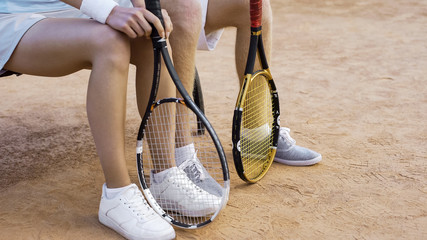 Young male and female tennis players waiting for match on bench, legs close-up