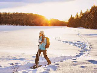 Wintersport vrouw wandelen in sneeuwschoenen. Sneeuwschoenmeisje in de sneeuw met schoenuitrusting om buiten te wandelen in het bospad. Québec, Canada.