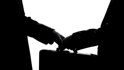 Businessman giving suitcase to partner, underground economy, illegal deal, bribe