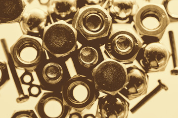 Art monochrome background from bolts and nuts close up in blue backlight. Macro photography of handful of fasteners in sepia tones.